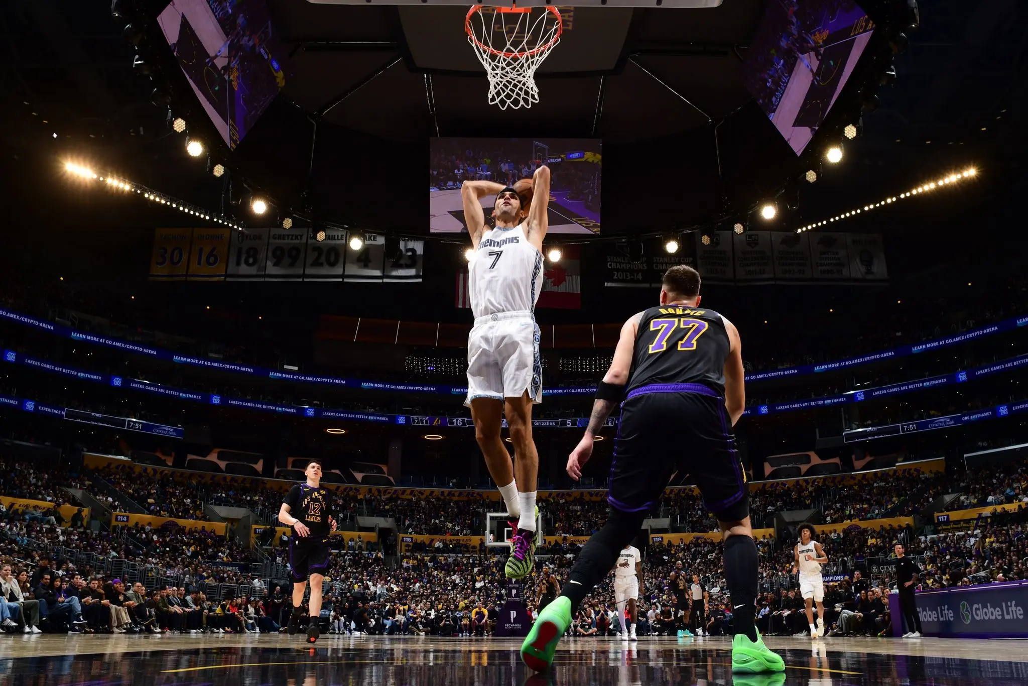 Santi Aldama en suspensión saltando hacia el aro para anotar frente a un defensor en un estadio de baloncesto profesional lleno de público