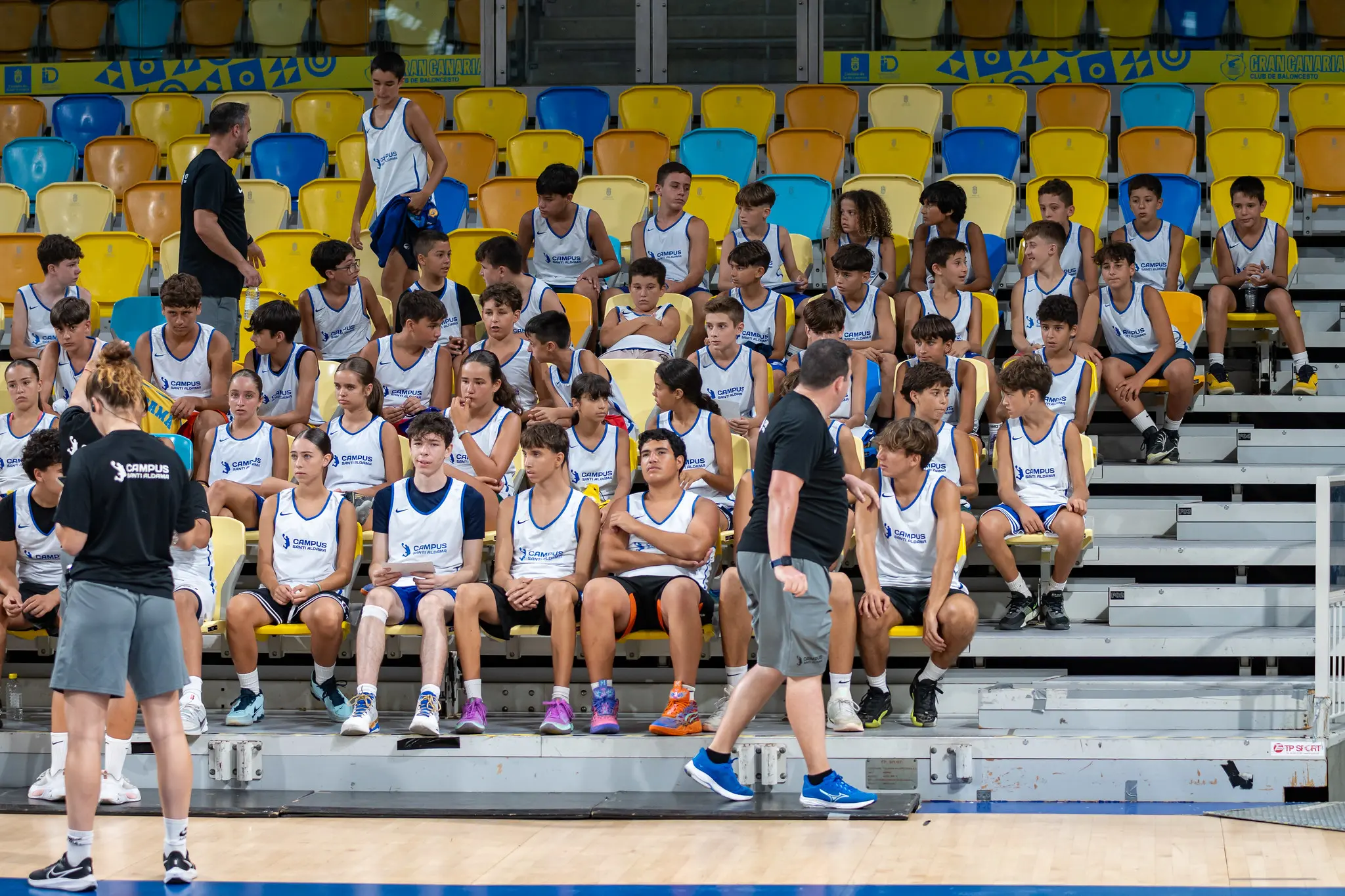 Alumnos del Campus Santi Aldama sentados en las gradas del Gran Canaria Arena atendiendo a las explicaciones del equipo técnico
