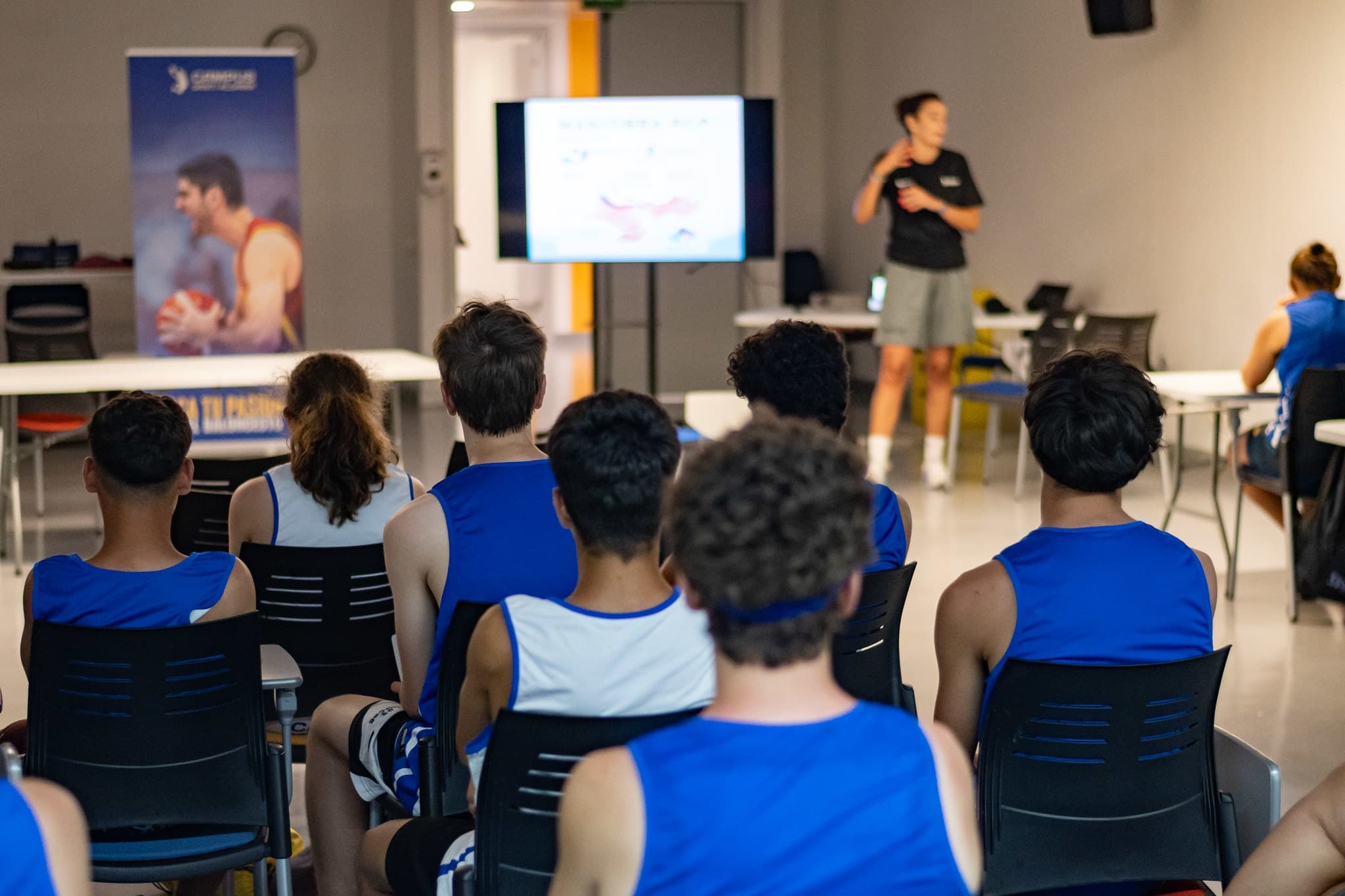 Alumnos del Campus Santi Aldama en una charla teórica en el aula con proyección y roll-up oficial del campus