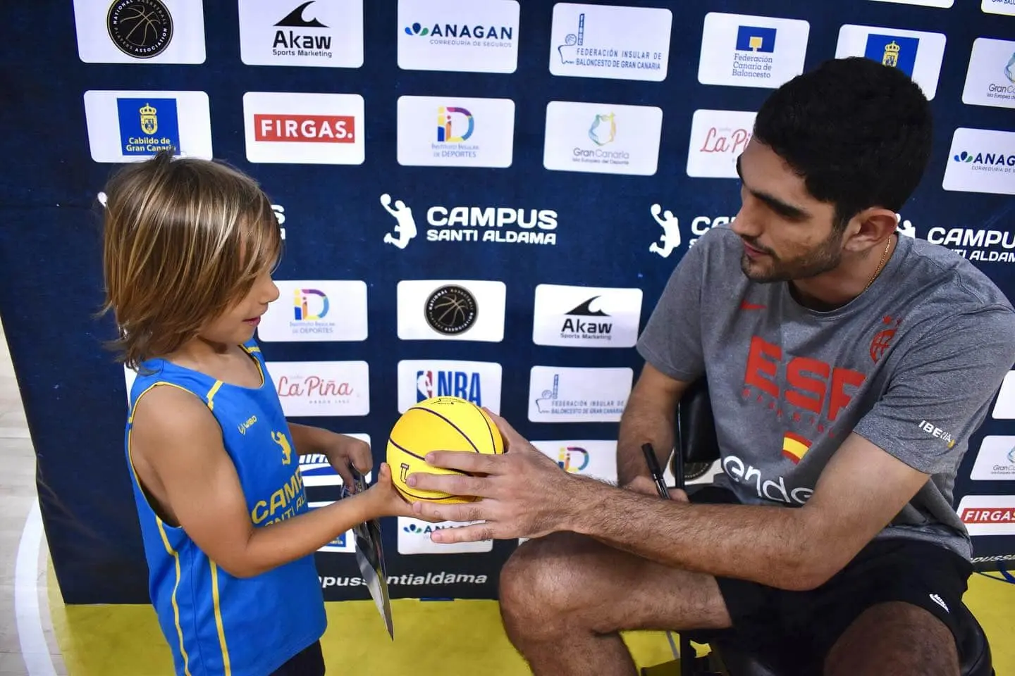 Santi Aldama interactuando con un niño participante del Campus Santi Aldama durante una sesión de fotos y firmas oficial