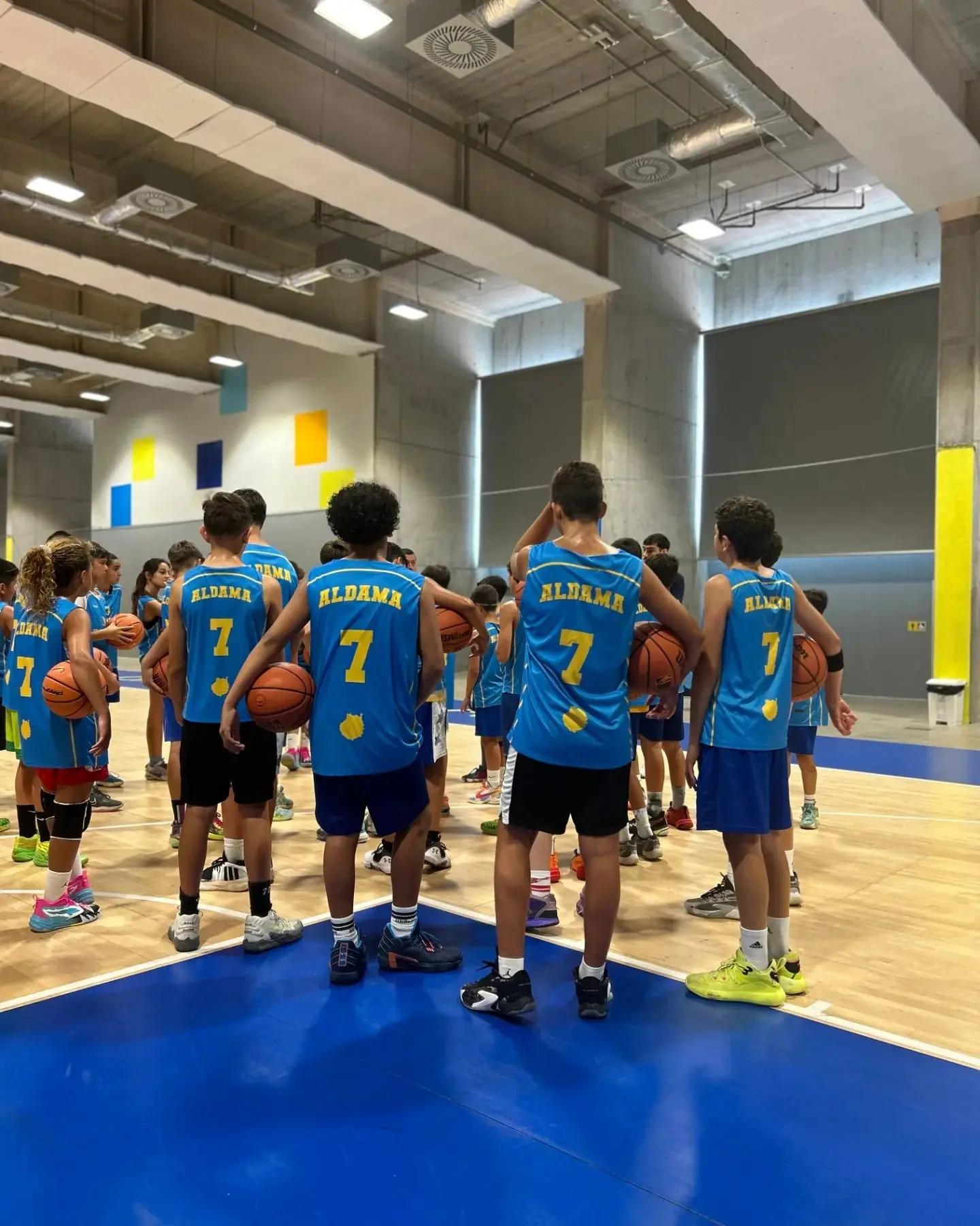 óvenes jugadores de espaldas luciendo la equipación oficial del Campus Santi Aldama durante una charla técnica sobre el trabajo en equipo